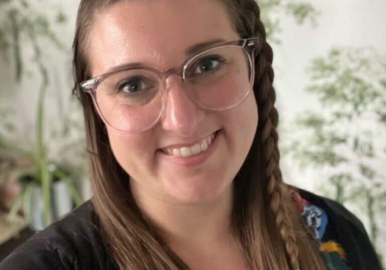 A headshot of Emilie, who wears glasses and a braid in her hair