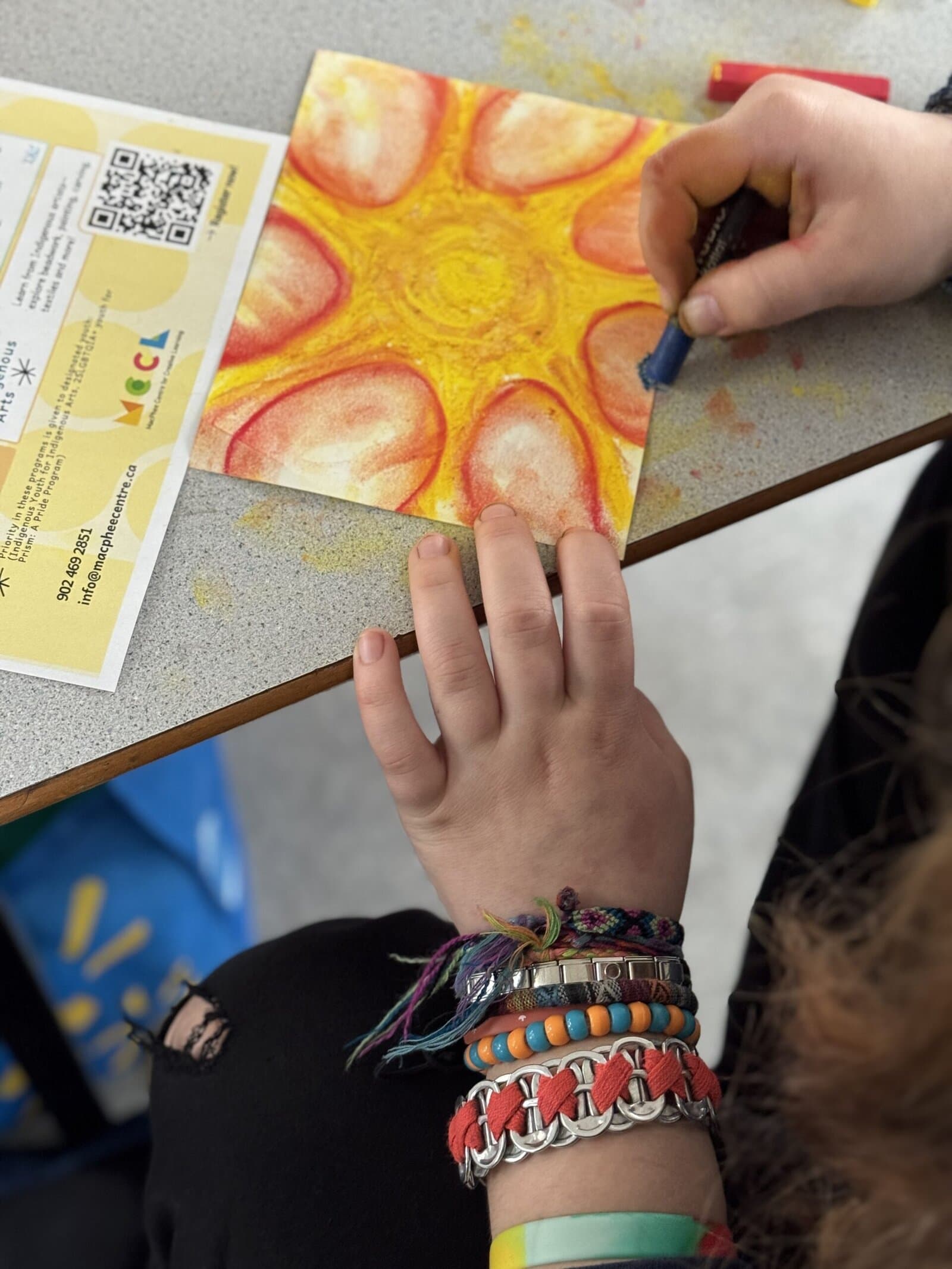Two hands use warm tone pastels to create abstract drawing.
